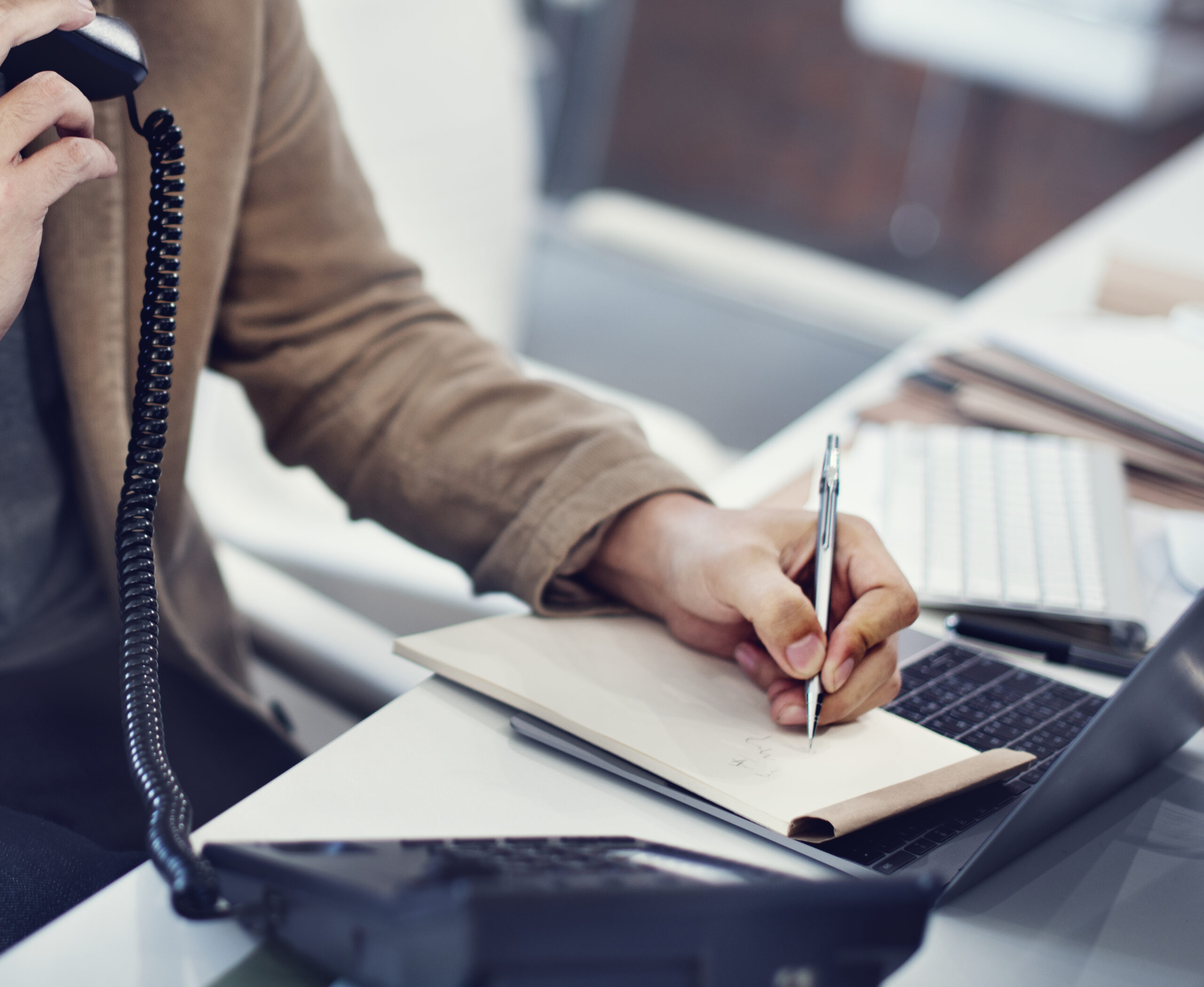 Hand writing a note beside a phone
